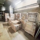 Imatge dels palets amb menjar, llits i estris de lavabo personal en un magatzem. A dalt a la dreta, anvers i revers d’una bossa amb una ració de menjar. - SCD