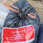 Un adhesiu sobre una bossa d’escombraries al carrer a la Pobla.