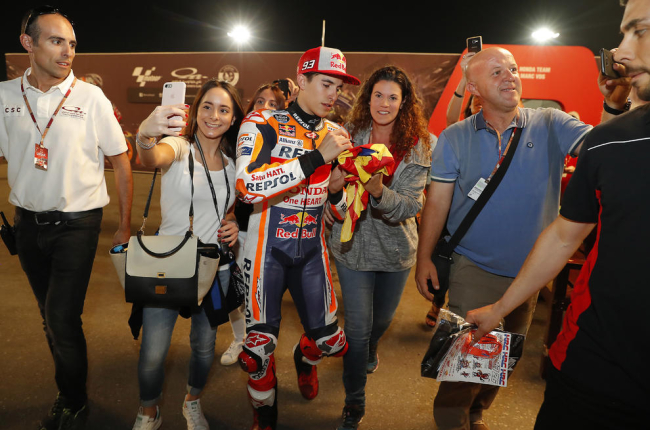 Marc Màrquez firma un autògraf a una aficionada, mentre altres es fan selfies amb el campió.