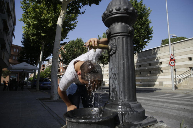 Un nen es refresca en una font en plena onada de calor a Lleida.