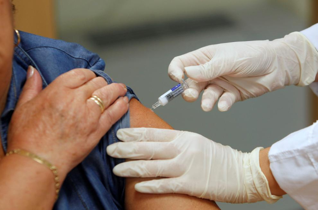 Una infermera posa una vacuna contra la grip.