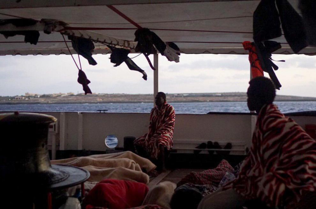 Alguns dels 147 migrants a la coberta del vaixell ‘Open Arms’ que ja es troben en aigües italianes, al davant l’illa de Lampedusa.