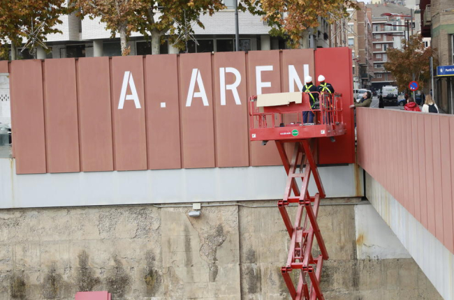 Operarios tapando ayer las grandes letras del rótulo de “A.Areny” de la pasarela de los Maristes.