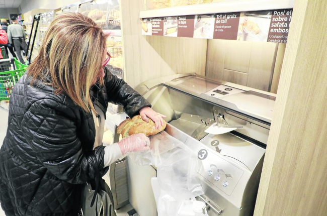 Una clienta talla el pa al seu gust al Mercadona erigit a la zona de l’antic Nou Forn de Lleida.