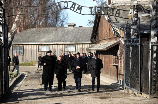 Merkel creua l’entrada del camp de concentració d’Auschwitz, sota el sinistre cartell “El treball us farà lliures”.