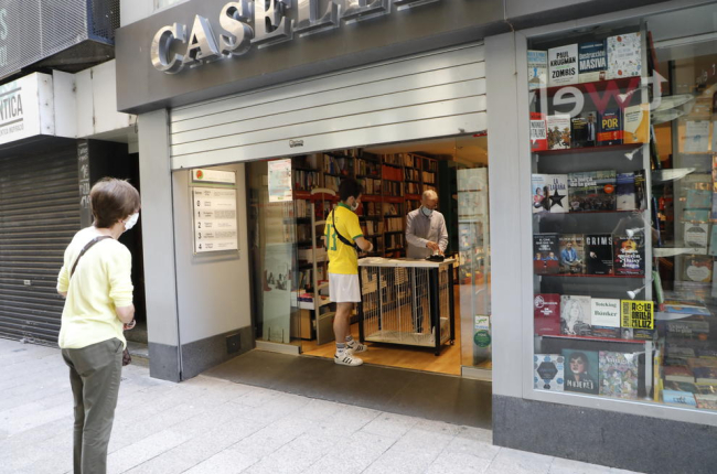 La librería Caselles de Lleida ayer, atendiendo a los clientes con cita previa en la puerta del comercio.