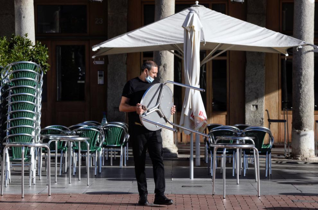 Un camarero monta la mesa de una terraza en Valladolid.