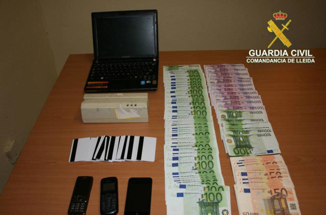 Imatge del material informàtic, les targetes, els mòbils i els diners confiscats als acusats.