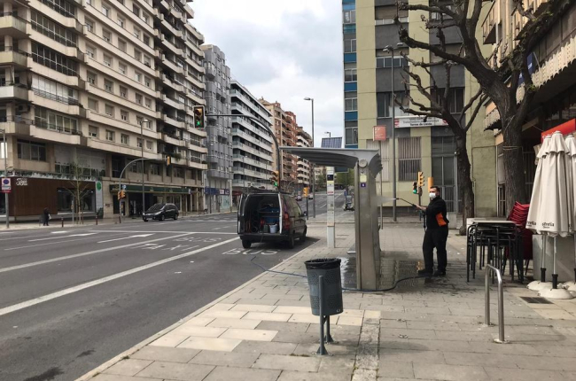 Un operari netejant una parada d’autobús a l’avinguda Catalunya, ahir al migdia.
