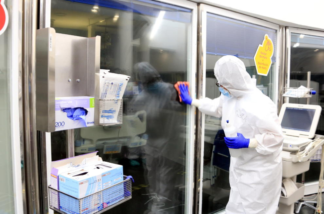 Una profesional sanitaria limpiando los cristales de una UCI con pacientes con covid-19 en el Hospital del Mar.