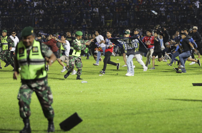 En la imagen, los hinchas saltan al campo ante el intento de la policía por contener la estampida.