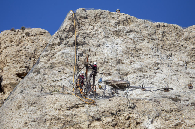 Los operarios trabajan verticalmente en la instalación de los anclajes en la roca para fijar la ladera.
