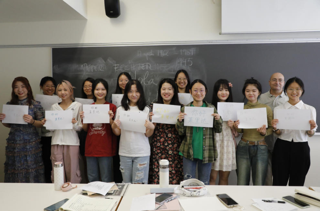 Tretze de les catorze estudiants xineses que han vingut aquest any posen amb uns cartells en xinès fets per elles que diuen “Hola, Lleida!”.