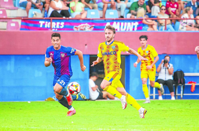 Juan Agüero persegueix una pilota amb un rival a l’aguait.