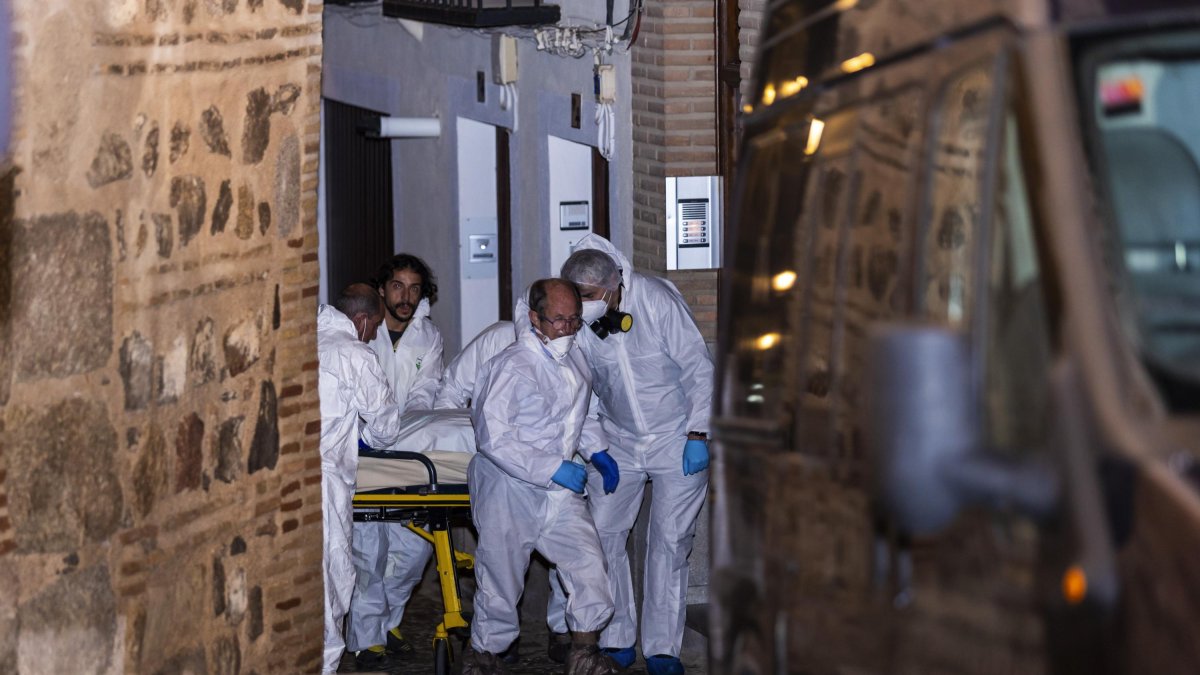 Miembros de los servicios funerarios trasportan uno de los cuatro cadáveres encontrados en una vivienda de Toledo.