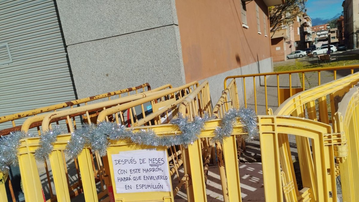 La valla, con la guirnalda navideña y el cartel con el pareado.