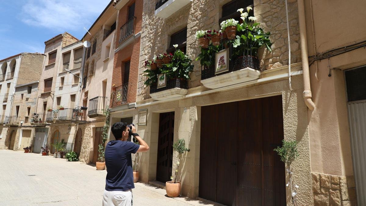 Un jove fotografia balcons engalanats al Soleràs (esquerra). A la dreta, flors al carrer i balcons dels Torms (a dalt) i detall d’una ornamentació al Soleràs. - MAGDALENA ALTISENT