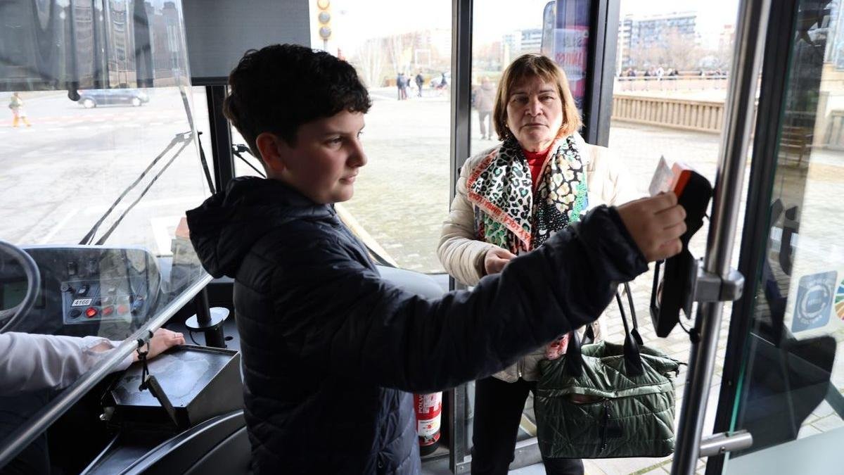 Dos viatgers validen el seu abonament de transport en un bus després de solucionar-se la incidència. - AMADO FORROLLA