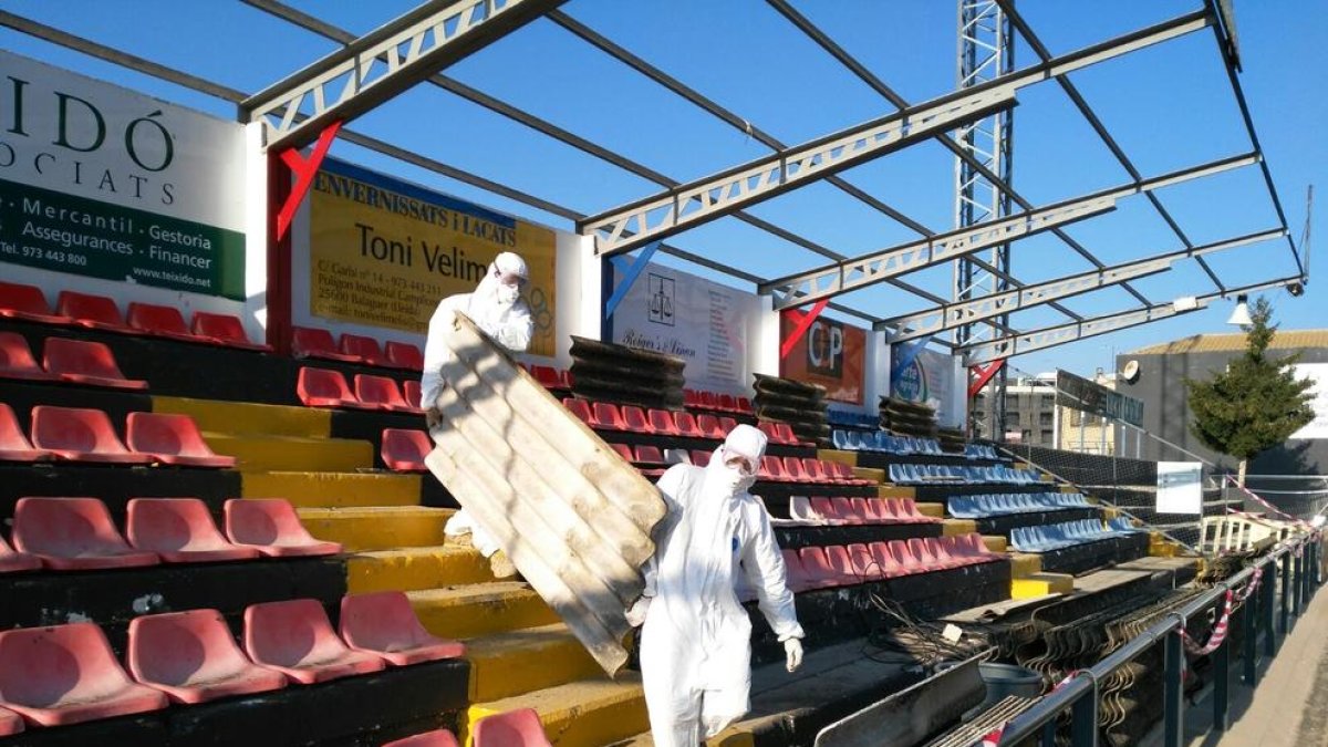 Operaris retiren, amb vestits especials, els trossos de coberta que contenen amiant.