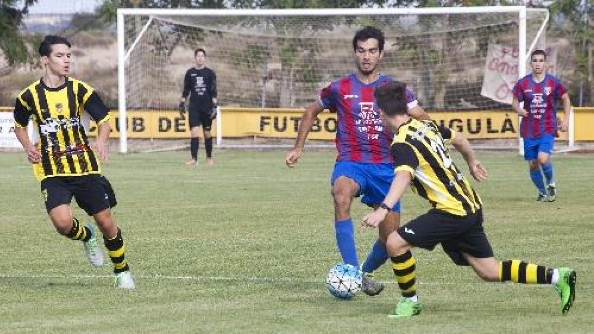 Un jugador del Torà controla l’esfèrica davant la pressió de dos jugadors de l’Angulària.