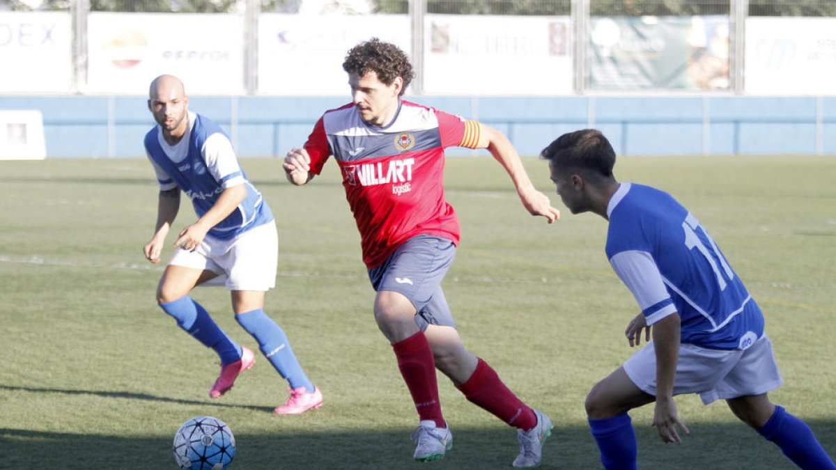 Carlos Martínez, que va entrar a la segona meitat, porta la pilota davant de la pressió de dos jugadors del Morell.
