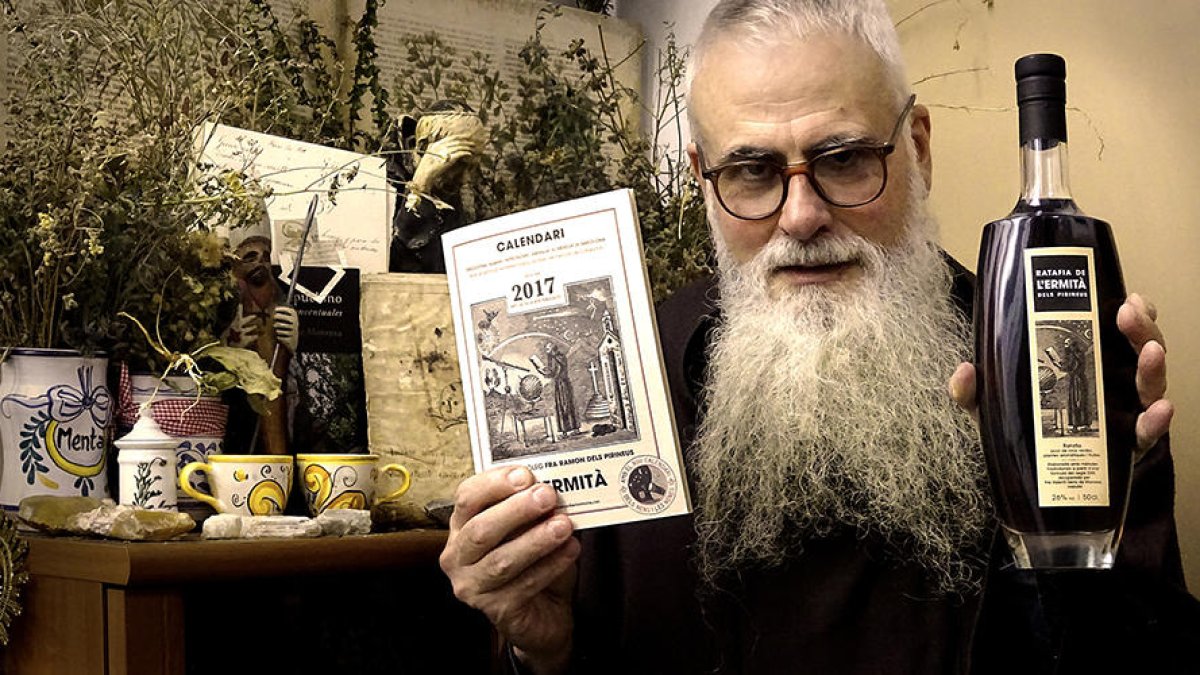 Un ermità mostrant una de les botelles de ratafia.
