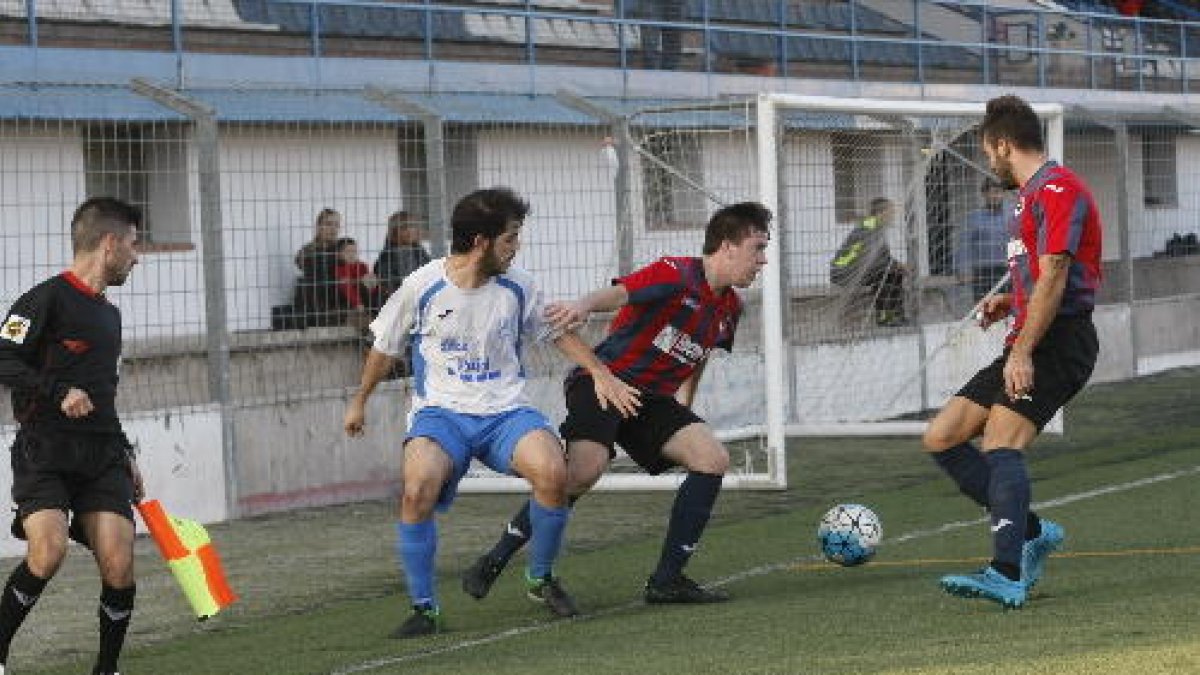Un jugador del Mollerussa pugna amb dos rivals per obtenir el control de la pilota a prop de la banda en una acció del partit.
