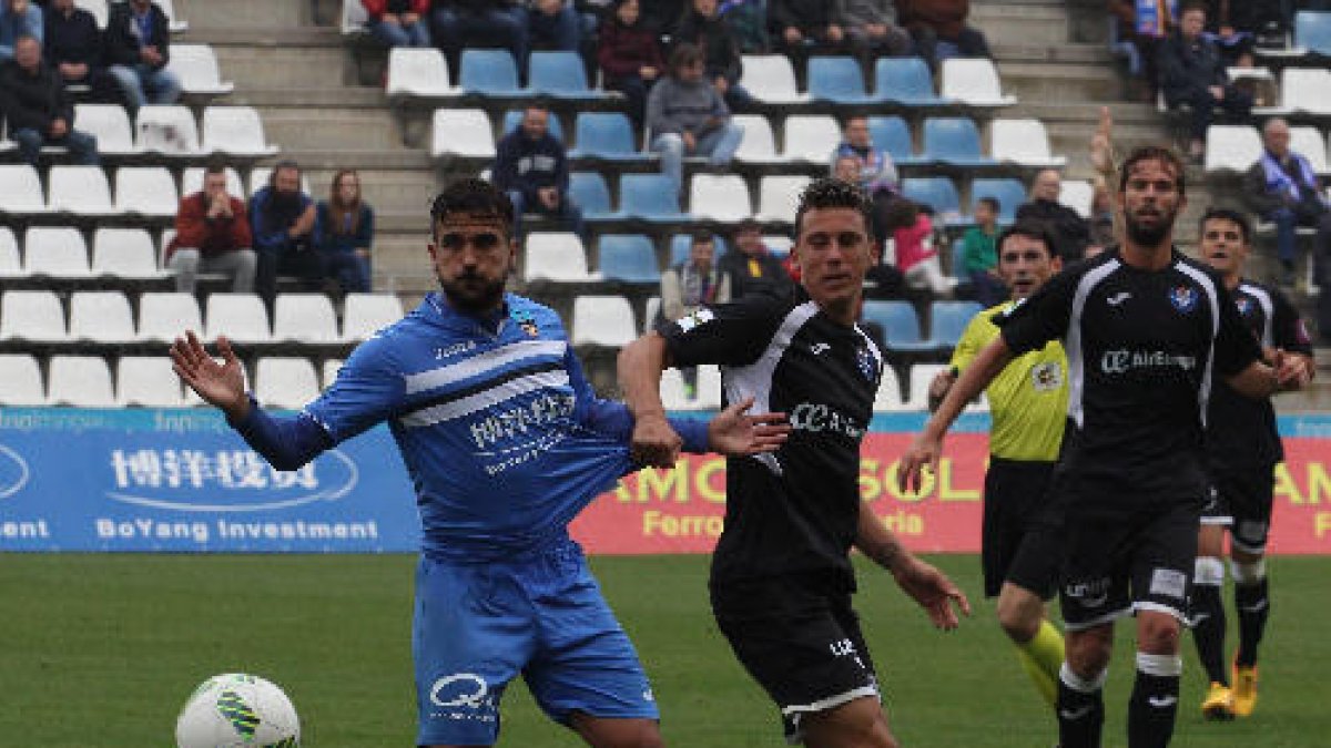 Guillem Martí disputa una pilota amb un defensa de l’Atlètic Balears que l’agafa de la samarreta.