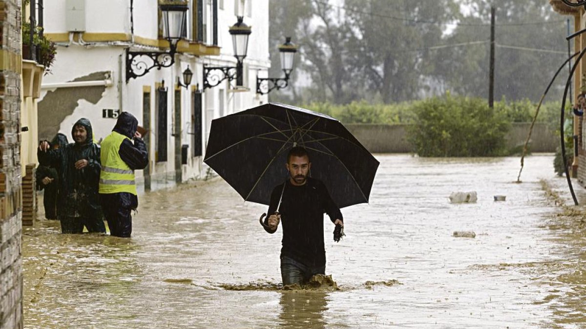 Un home camina entre les cases inundades a la barriada Doña Ana de la localitat malaguenya de Cártama per les fortes pluges.