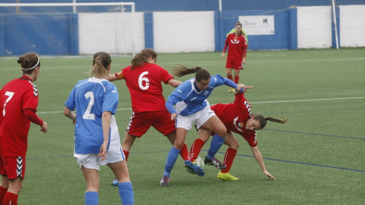 Una jugadora del AEM trata de salir de la presión de dos futbolistas rivales.