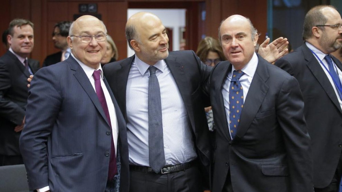 Moscovici saluda a Luis de Guindos y al ministro francés de Finanzas durante la reunión del Eurogrupo.