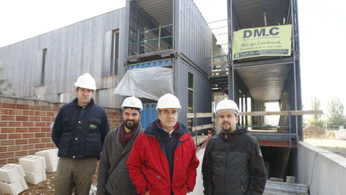 Els constructors, els promotors i l’arquitecte, davant dels contenidors que formen l’estructura de la casa de Ciutat Jardí.