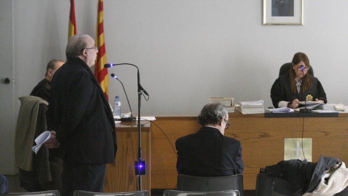 Josep Calbetó, declarando de pie como testigo, y Joan Riu, sentado en el banquillo, en el juicio de ayer.
