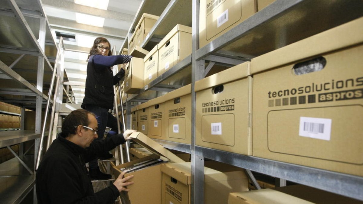 Dos dels treballadors d’aquesta empresa d’Aspros, ahir, al magatzem on es custodien els documents.