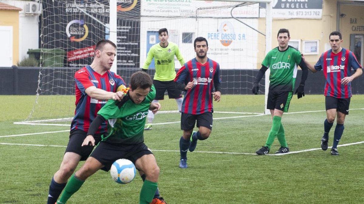 Un jugador del Cervera controla la pilota davant de l’oposició d’un defensa del Tàrrega durant el partit disputat ahir al Municipal Joan Capdevila.