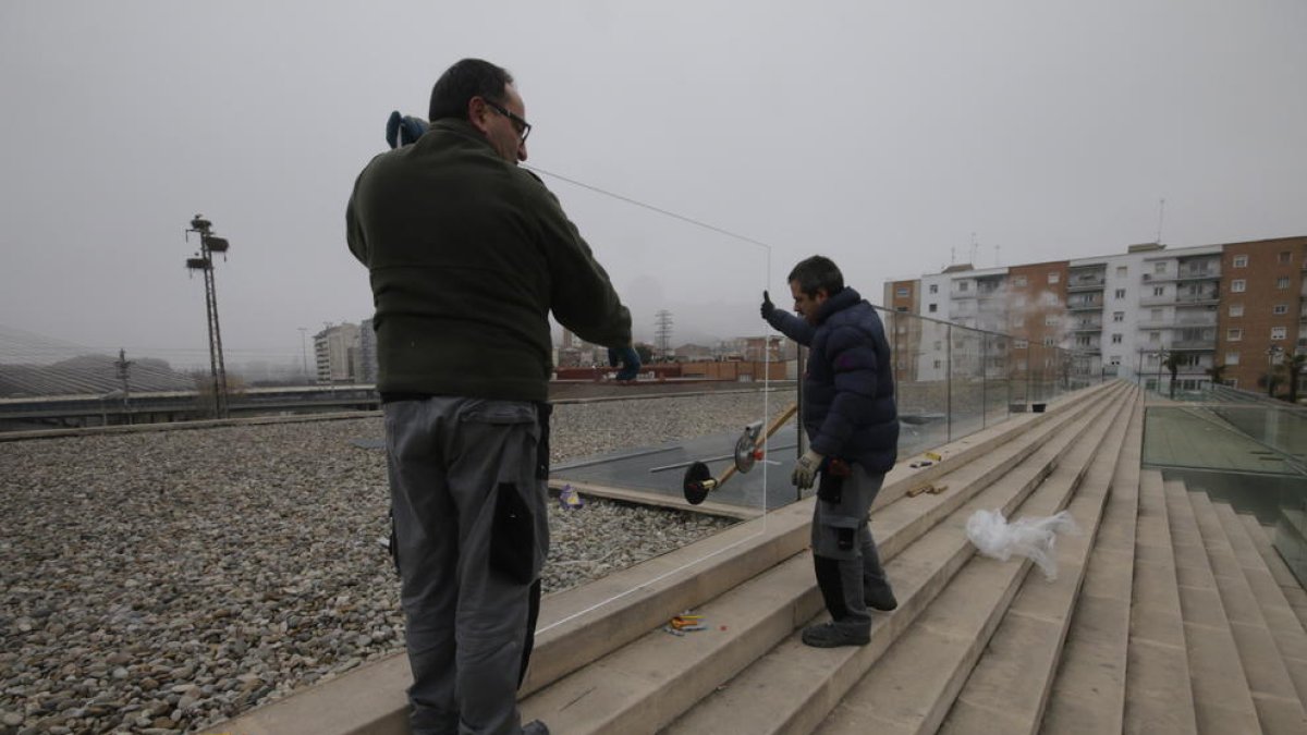 Dos operarios, instalando ayer las nuevas mamparas en las escaleras frente a la Llotja.