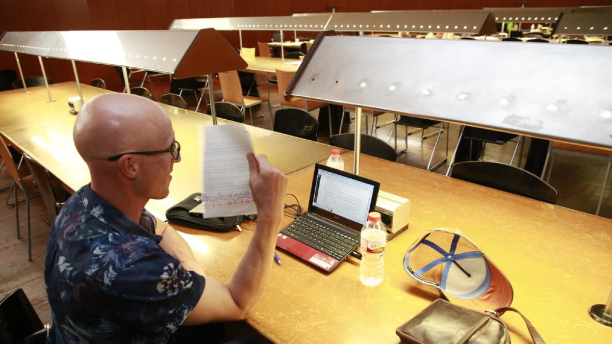Un usuario de la sala, ayer por la tarde abanicándose con una hoja de papel para combatir el calor.