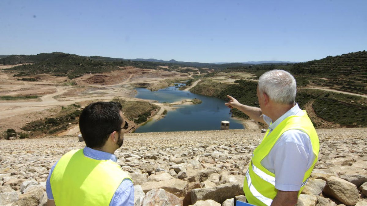 Josep Maria Serra (d.), junto al responsable de la empresa, muestra la zona inundada de la presa, con unos 400.000 metros cúbicos de agua.