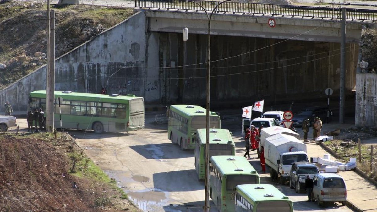 Diversos operaris d’autobusos esperen a començar l’evacuació dels combatents a Alep.