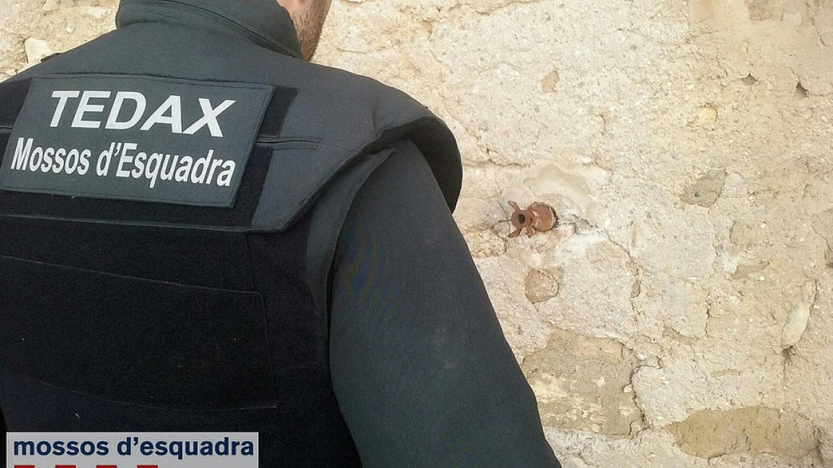Un agent dels Tedax observa la granada de morter encastada a la paret de la casa.