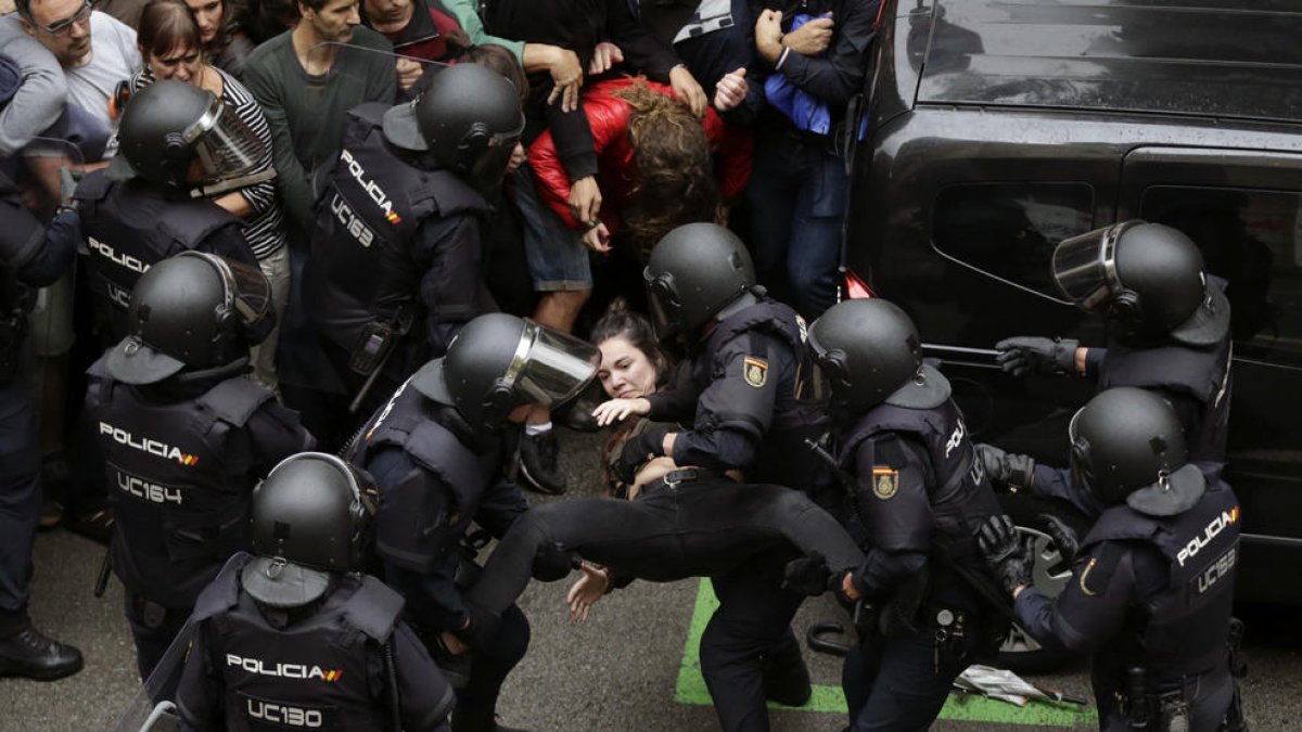 Els agents de la Policia Nacional formen un cordó policial al col·legi Ramon Llull i s’emporten una noia.