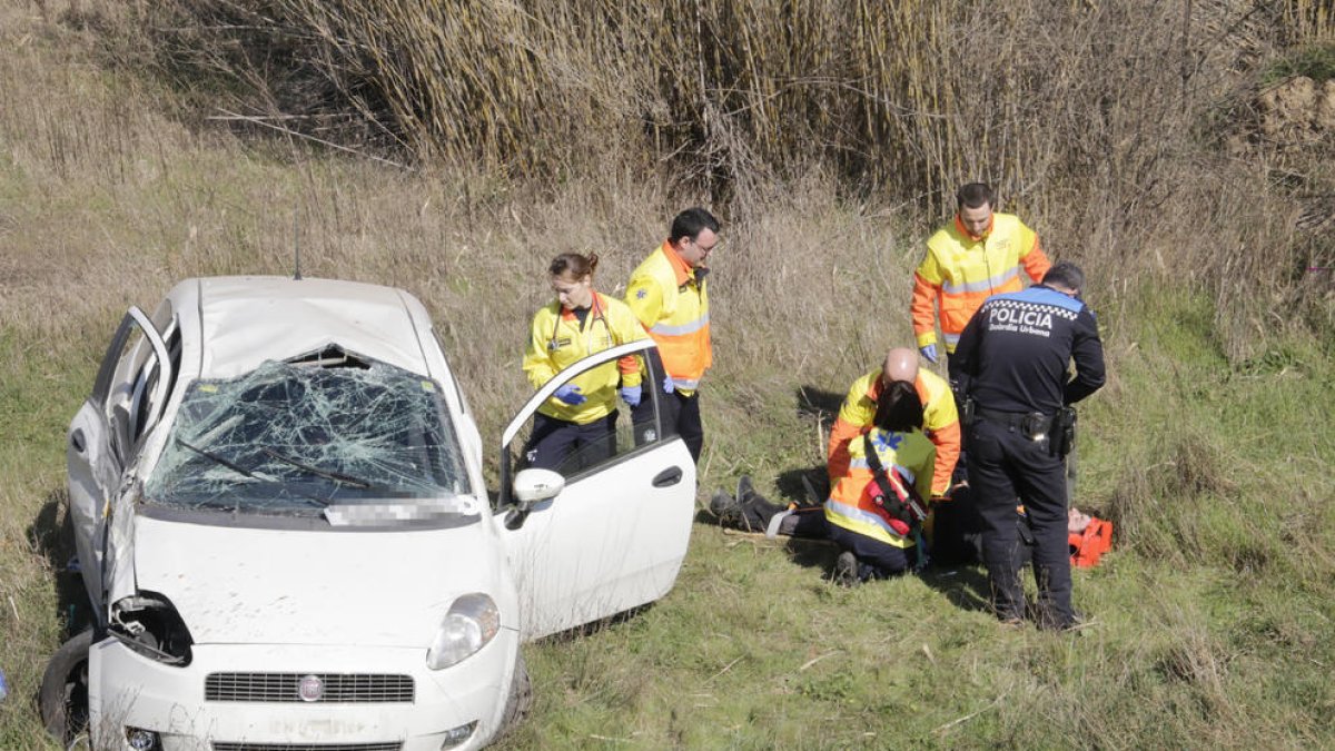 Los servicios de emergencia atienden al herido, después de que su coche volcara.