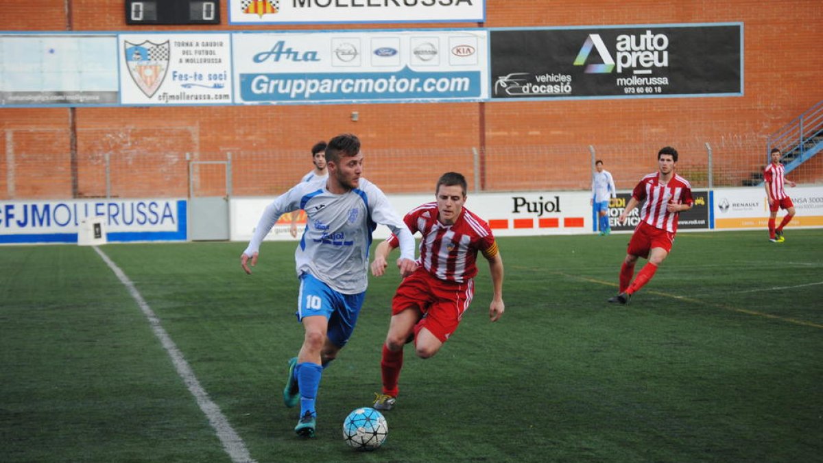 El local Edu Raya conduce un balón ante la oposición de un jugador rival durante un lance del partido.