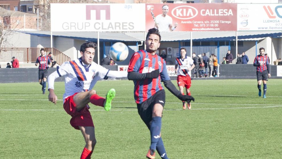 Un jugador de la UE Tàrrega intenta endur-se una pilota davant l’oposició d’un adversari.