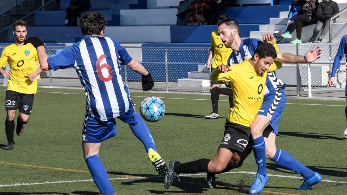 Un jugador del Lleida Esportiu B, ahir de groc, cau davant de la pressió de dos rivals.