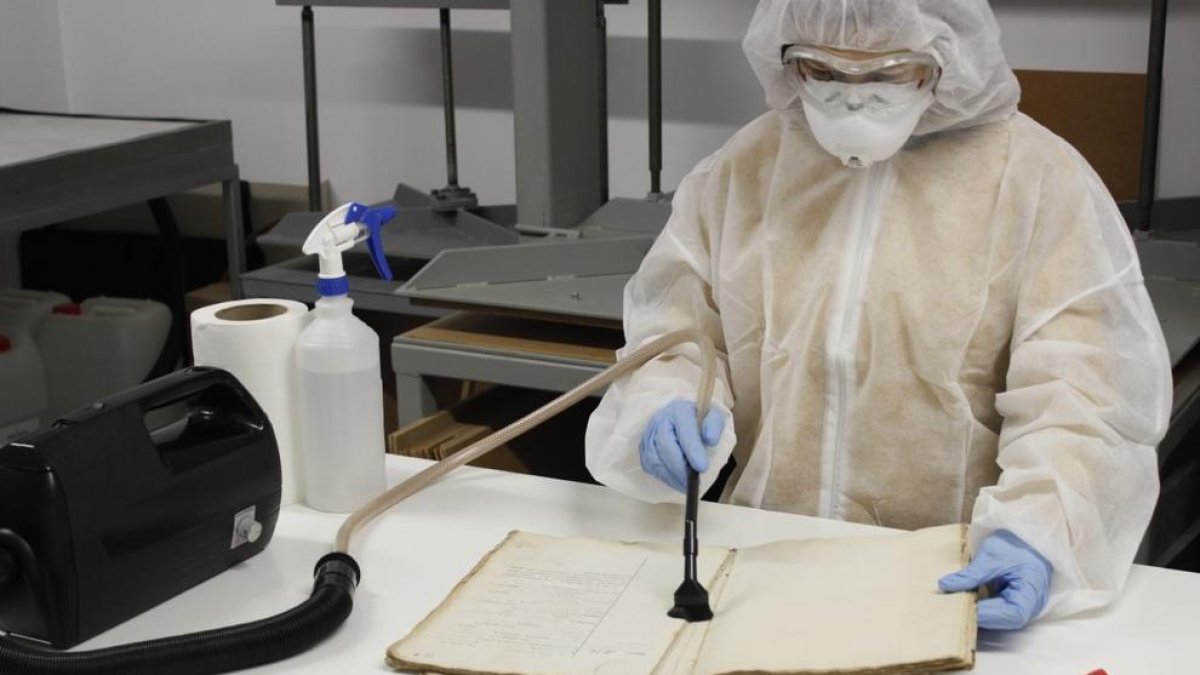 Núria Vila duent a terme les tasques de desinfecció d’un llibre.