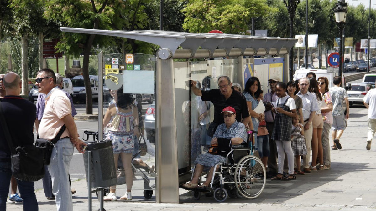 Usuarios del autobús “refugiados” en la zona de sombra de una marquesina ayer al mediodía.