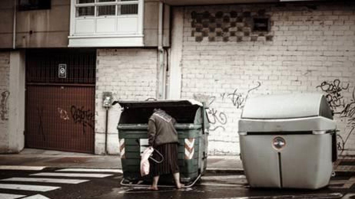 Una persona buscando en un contenedor.