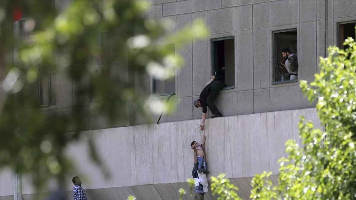 Policías iraníes ayudan a escapar a civiles después de que hombres armados entraran en el Parlamento.