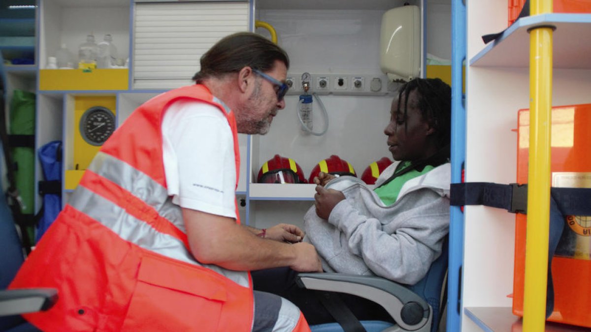 Un membre dels serveis de salvament atén una dona embarassada arribada en una pastera.